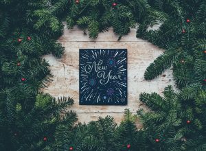 Happy New Year sign surrounded by pine tree branches